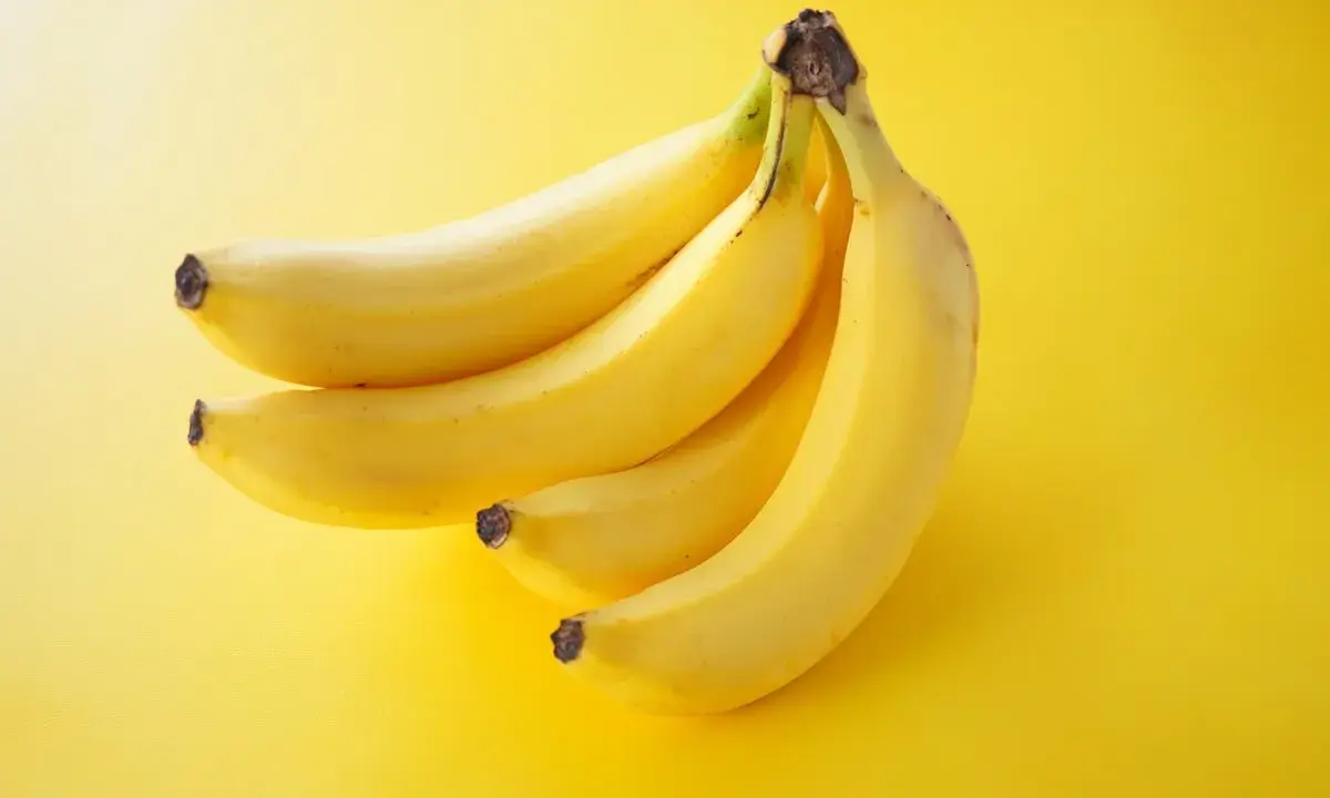 Pęczek żółtych bananów na jaskrawożółtym tle. Idealna przekąska, która dostarczy energii i nie obciąży zbytnio kalorycznie.