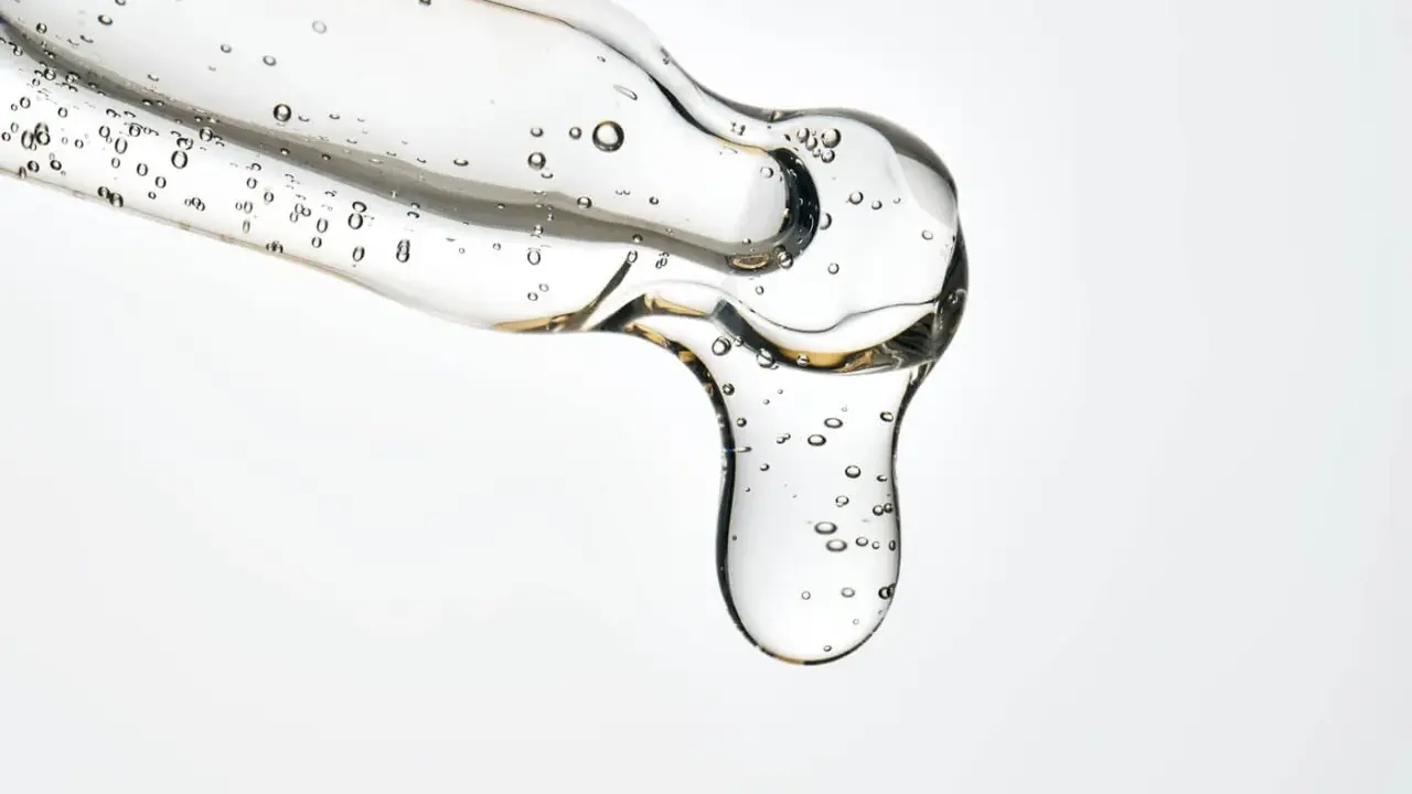 Kwas salicylowy działanie: przejrzysty żel z pęcherzykami powietrza spływa z pipety, obiecując czystą i odświeżoną skórę.