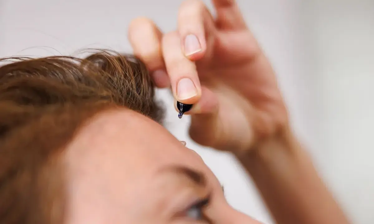 Dłoń z kropelką serum, zbliżającą się do czoła. To moment retinal climax, pielęgnacji dla skóry.