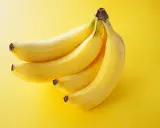 Pęczek żółtych bananów na jaskrawożółtym tle. Idealna przekąska, która dostarczy energii i nie obciąży zbytnio kalorycznie.