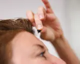 Dłoń z kropelką serum, zbliżającą się do czoła. To moment retinal climax, pielęgnacji dla skóry.