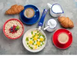 Pyszne, lekkostrawne śniadanie: owsianka z owocami, jajka sadzone z groszkiem, dwa croissanty i kawa. Idealny początek dnia!
