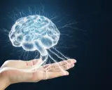 Dłoń trzymająca świetlisty mózg, z którego emanują impulsy energii. To symbol potęgi umysłu i jego połączenia ze światem, niczym tajemnicza szyszynka.