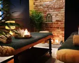Dwie łóżka do masażu w przytulnym spa, ozdobione świecami i roślinami.