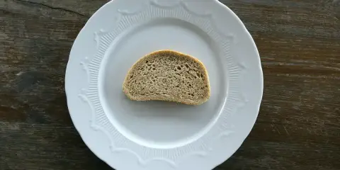 Jeden plasterek chleba tostowego na białym talerzu. Zastanawiasz się nad jego kcal?