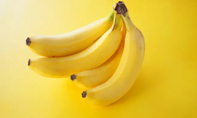 Pęczek żółtych bananów na jaskrawożółtym tle. Idealna przekąska, która dostarczy energii i nie obciąży zbytnio kalorycznie.