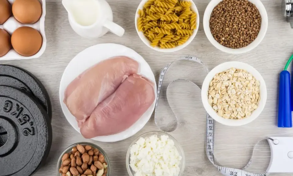 Składniki na dietę na masę mięśniową: kurczak, jajka, mleko, płatki owsiane, makaron, kasza gryczana, orzeszki ziemne, twaróg, hantle i skakanka.